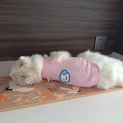 Display of pink pet vests in various sizes laid out on a table with small stuffed animals
